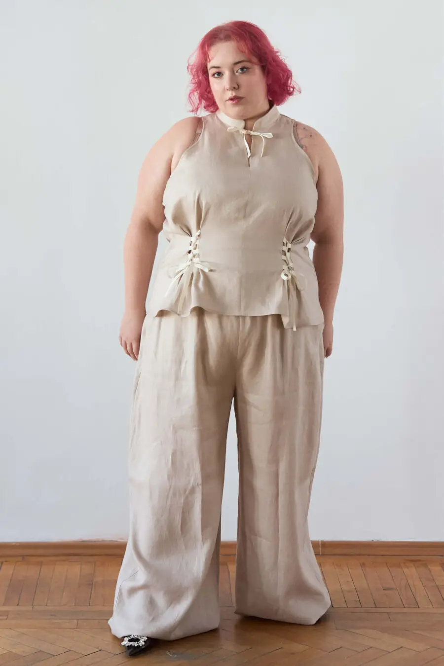 Yvonne sleeveless corset shirt in beige - A sleeveless halter-style shirt made from pink gingham with a structured silhouette and corset-inspired lacing at the waist.