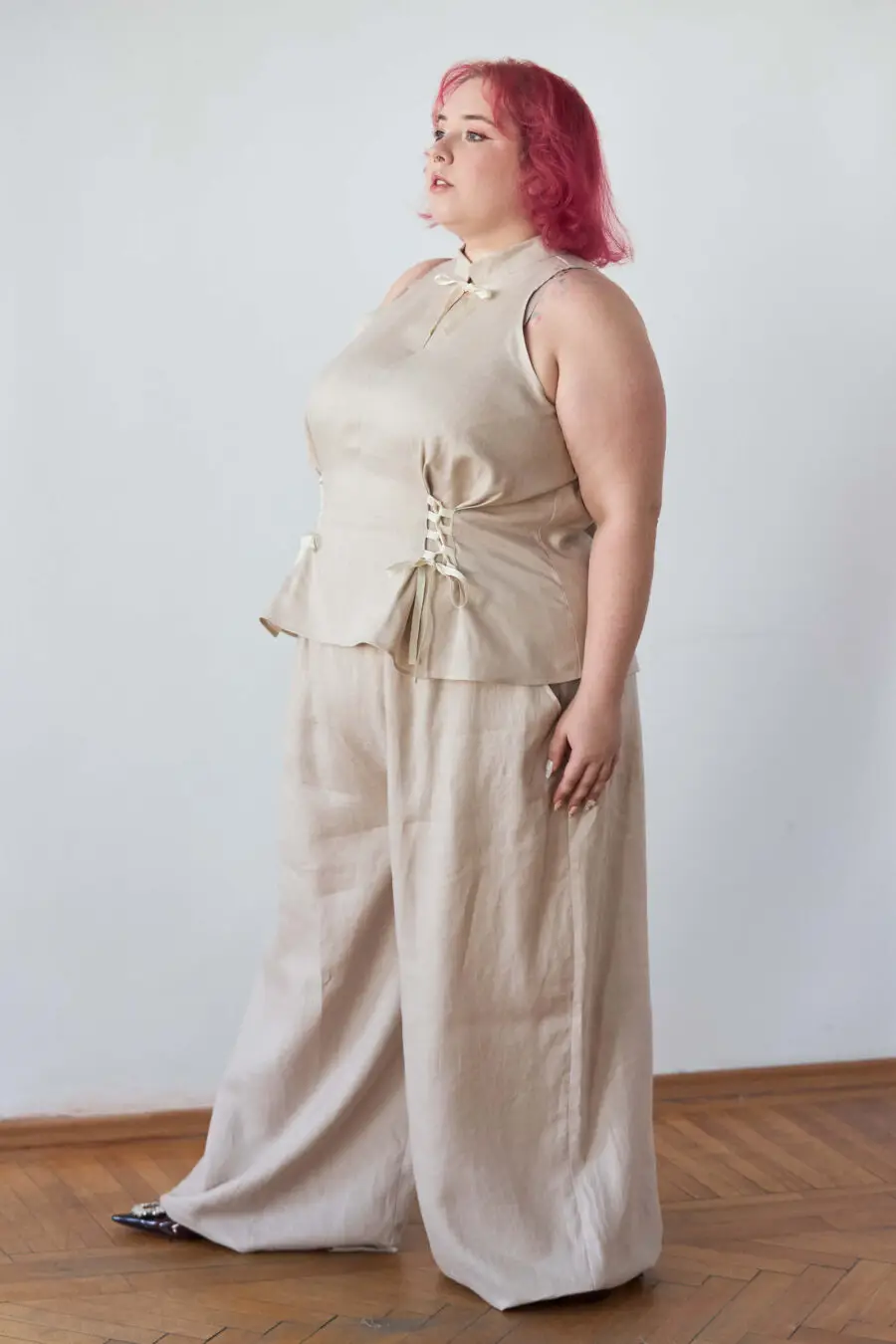 Yvonne sleeveless corset shirt in beige - A sleeveless halter-style shirt made from pink gingham with a structured silhouette and corset-inspired lacing at the waist.