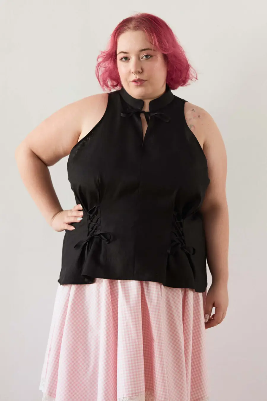 Yvonne sleeveless corset shirt in black - A sleeveless halter-style shirt made from pink gingham with a structured silhouette and corset-inspired lacing at the waist.
