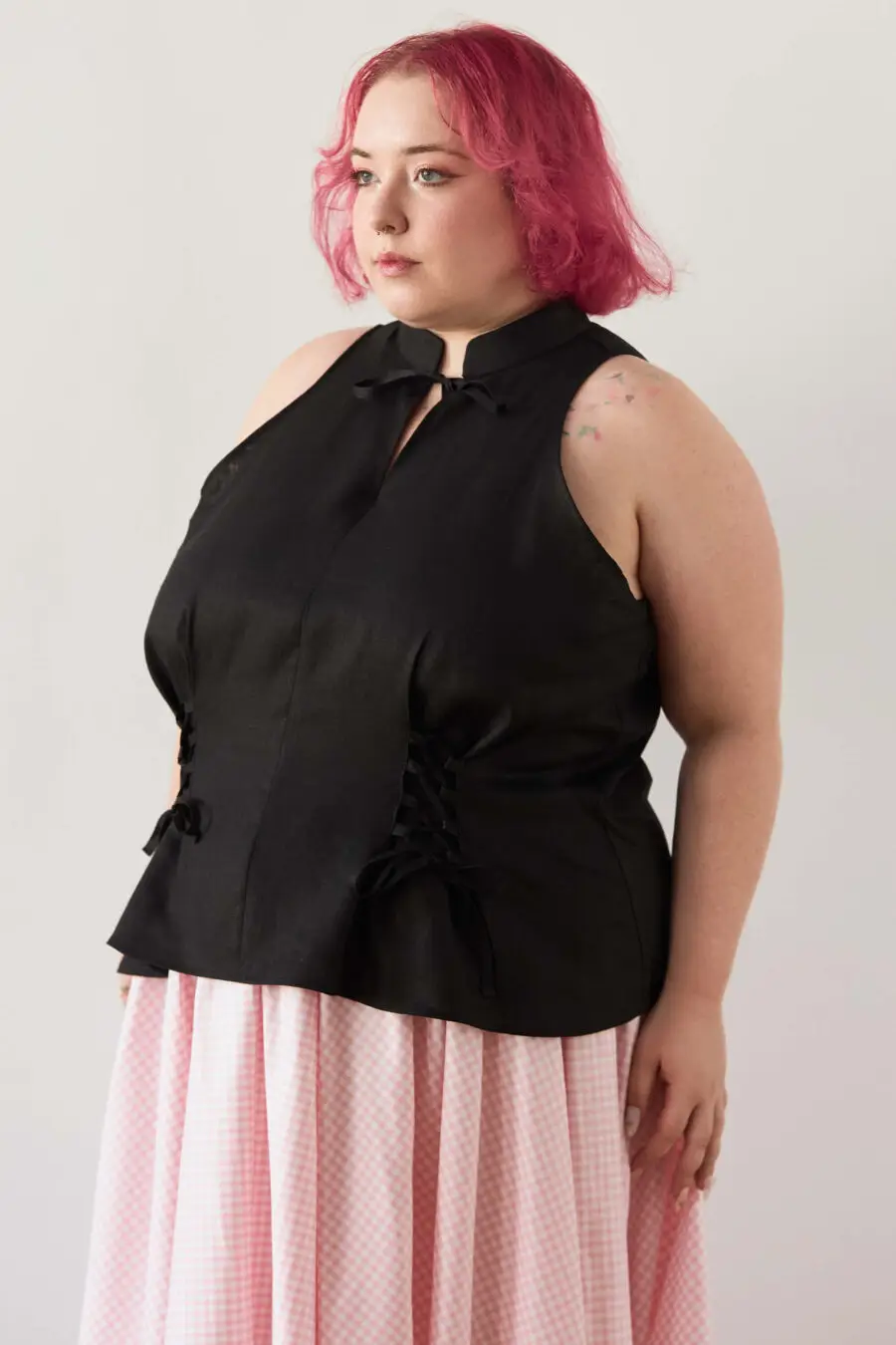 Yvonne sleeveless corset shirt in black - A sleeveless halter-style shirt made from pink gingham with a structured silhouette and corset-inspired lacing at the waist.