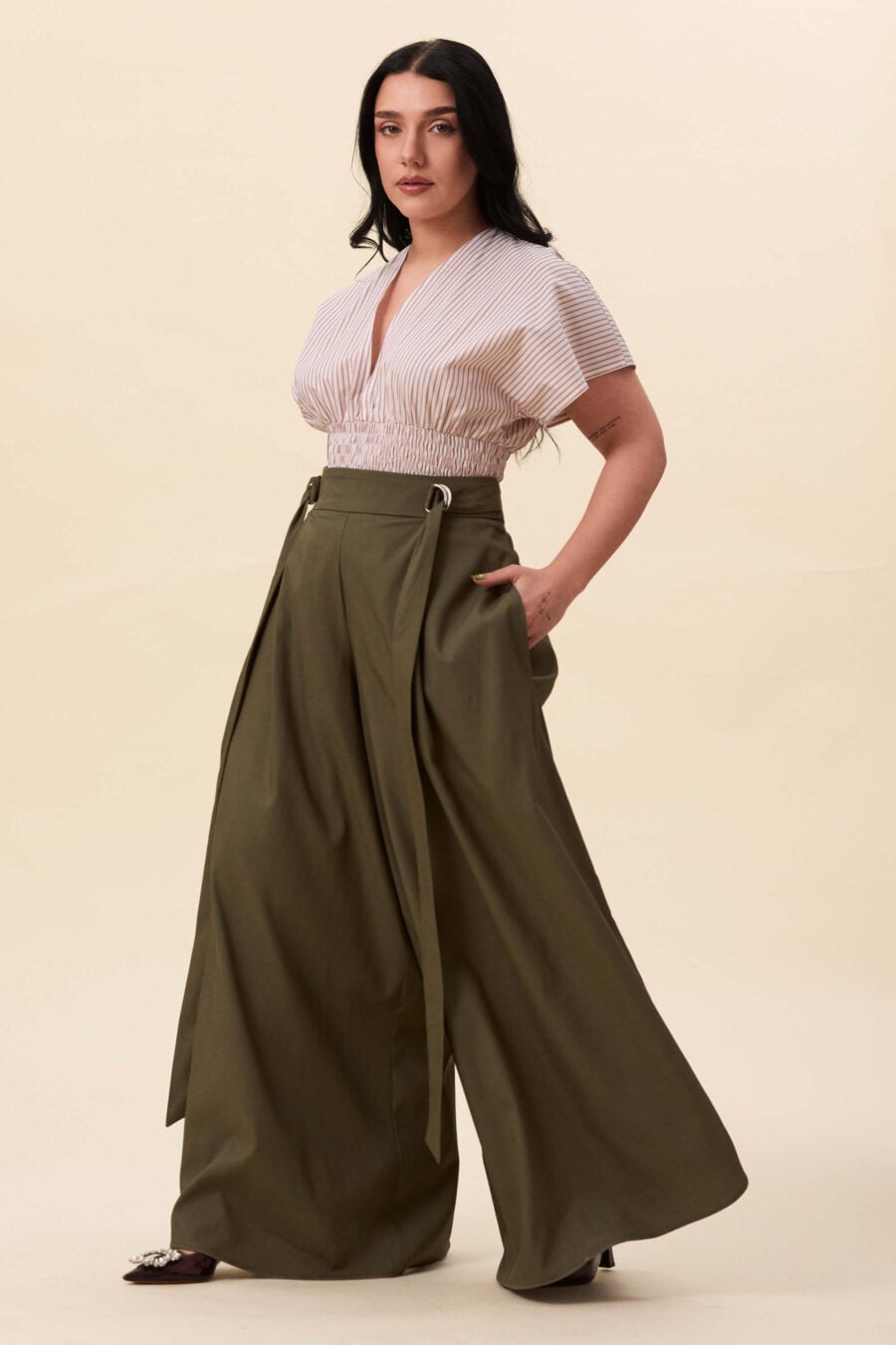 Amelia Peabody palazzo pants in olive green  A full, elongated line shaped by a high, structured waist. The fit is adjusted through a double Dring belt, introducing function without excess detail. From there, the trousers fall wide and uninterrupted.