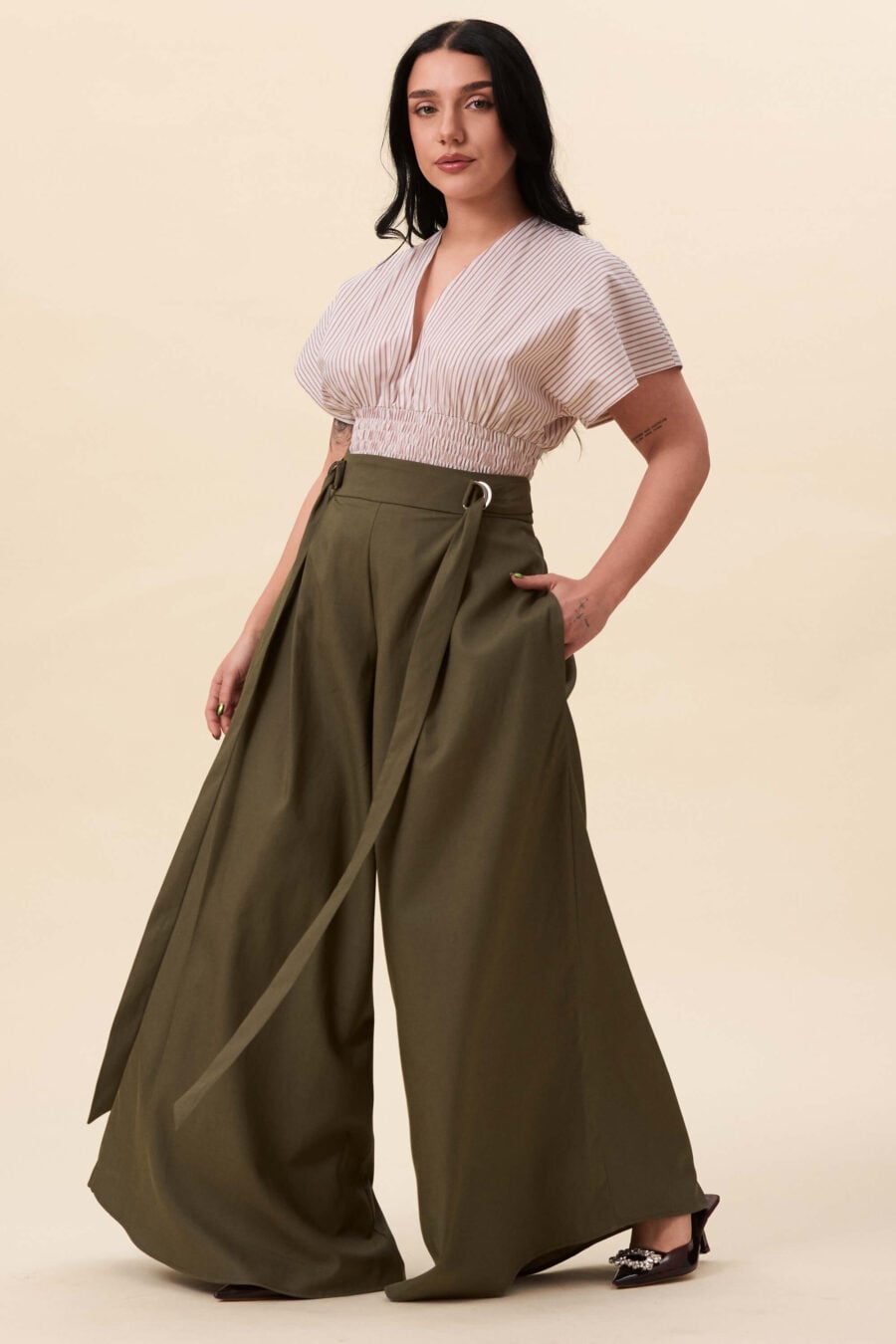 Amelia Peabody palazzo pants in olive green - A full, elongated line shaped by a high, structured waist. The fit is adjusted through a double D-ring belt, introducing function without excess detail. From there, the trousers fall wide and uninterrupted.