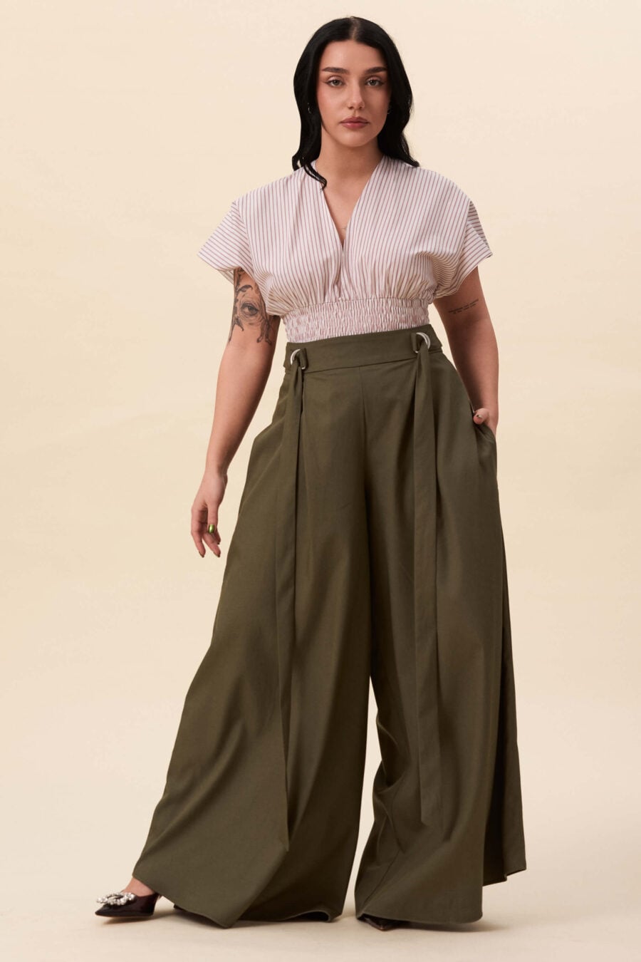 Amelia Peabody palazzo pants in olive green - A full, elongated line shaped by a high, structured waist. The fit is adjusted through a double D-ring belt, introducing function without excess detail. From there, the trousers fall wide and uninterrupted.