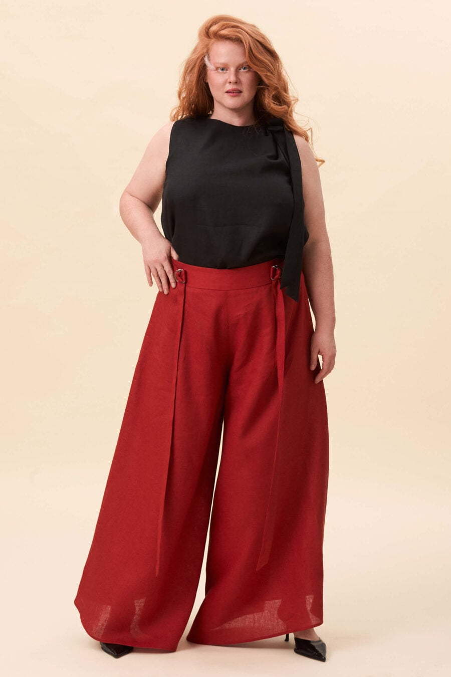 Amelia Peabody palazzo pants in tomato red  A full, elongated line shaped by a high, structured waist. The fit is adjusted through a double Dring belt, introducing function without excess detail. From there, the trousers fall wide and uninterrupted.