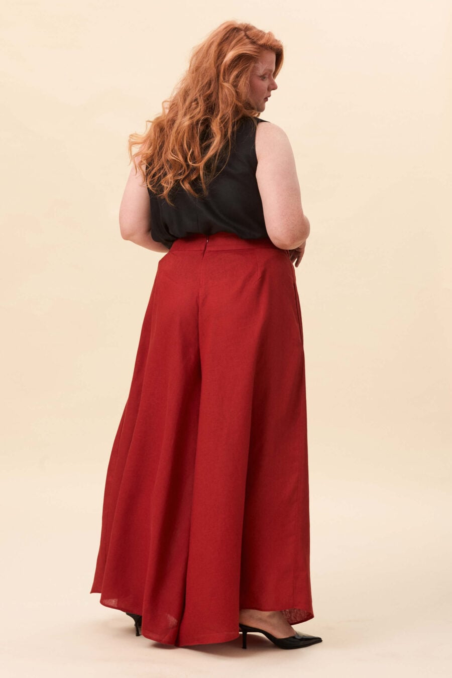 Amelia Peabody palazzo pants in tomato red - A full, elongated line shaped by a high, structured waist. The fit is adjusted through a double D-ring belt, introducing function without excess detail. From there, the trousers fall wide and uninterrupted.