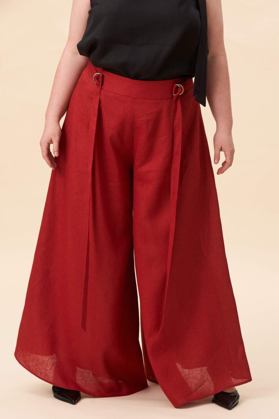 Amelia Peabody palazzo pants in tomato red - A full, elongated line shaped by a high, structured waist. The fit is adjusted through a double D-ring belt, introducing function without excess detail. From there, the trousers fall wide and uninterrupted.