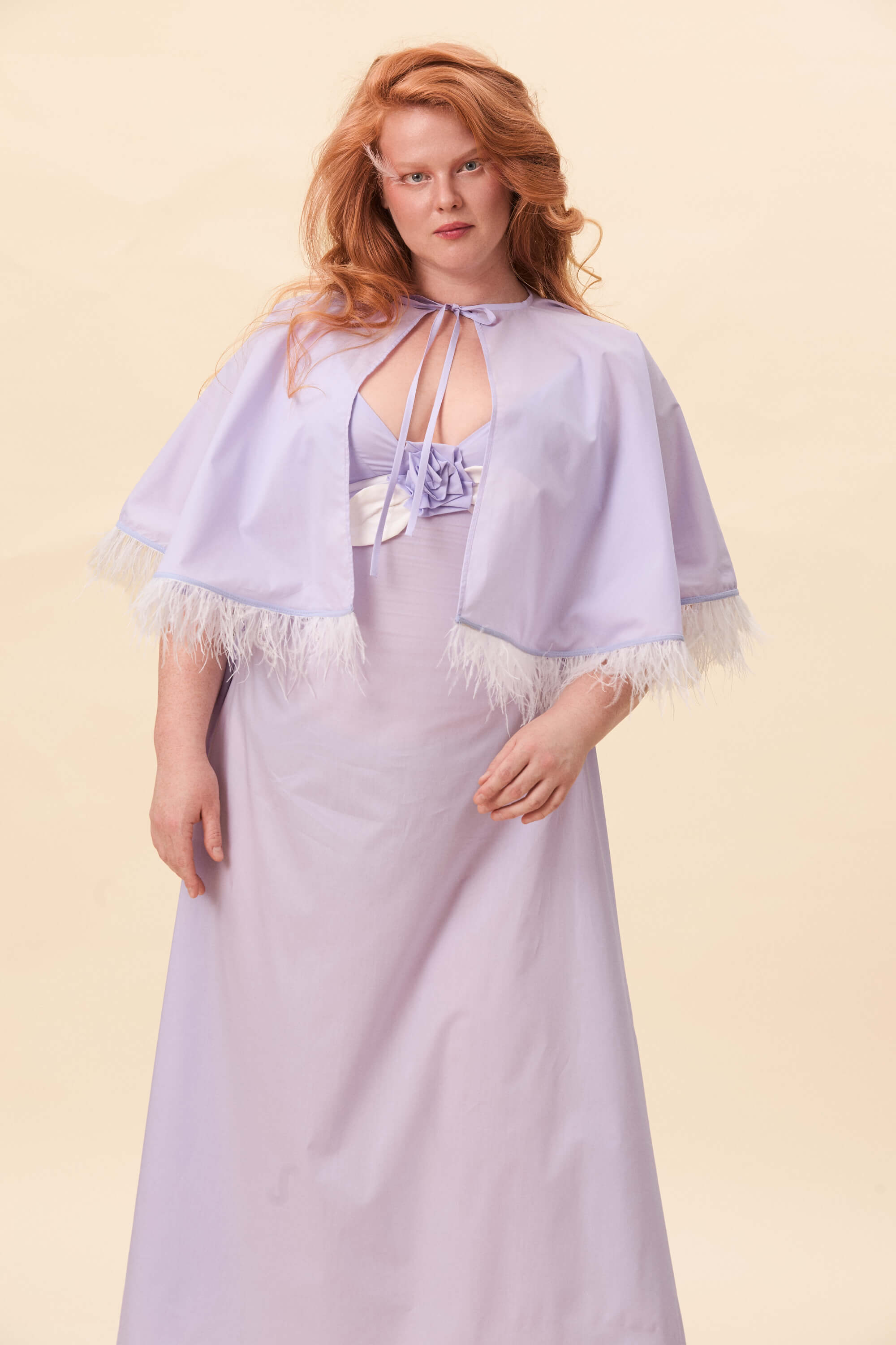 Spring 2026 Birds Of A Feather Cape In Lavender Voille 4 Birds Of A Feather Cape In Lavender Voille Birds of a Feather cape in lavender voille Cut in a short, flared silhouette that rests lightly on the shoulders. The cape ties at the neck, creating a clean opening through the front. Along the edge, a feather trim introduces texture and subtle motion. Balanced between structure and softness.