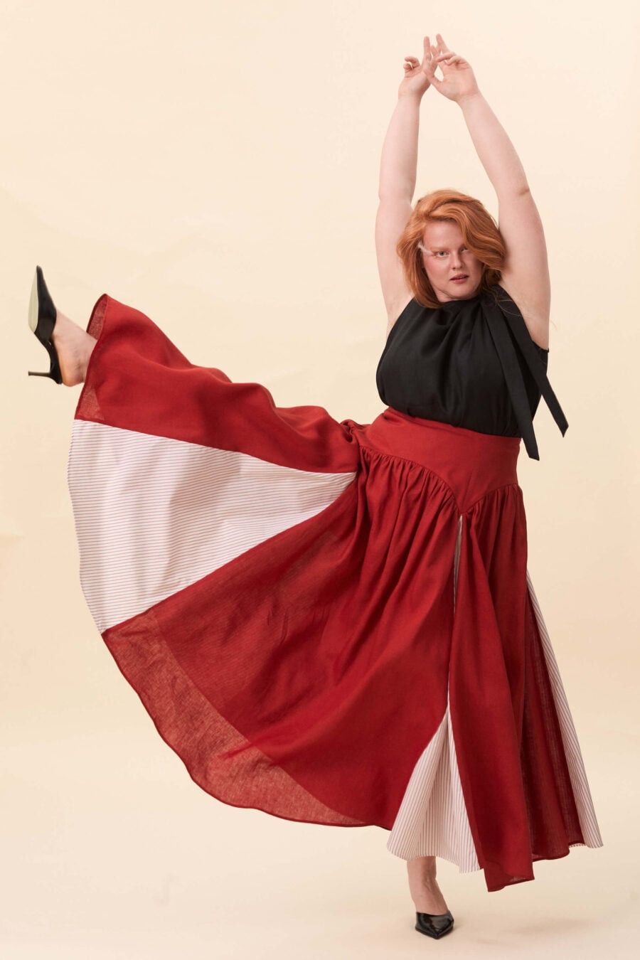 Cordelia Gray maxi skirt in tomato red - The waist holds a fitted structure before releasing into a full, gathered skirt. Contrasting panels at the front and back shape the silhouette, introducing variation and rhythm as the garment moves.