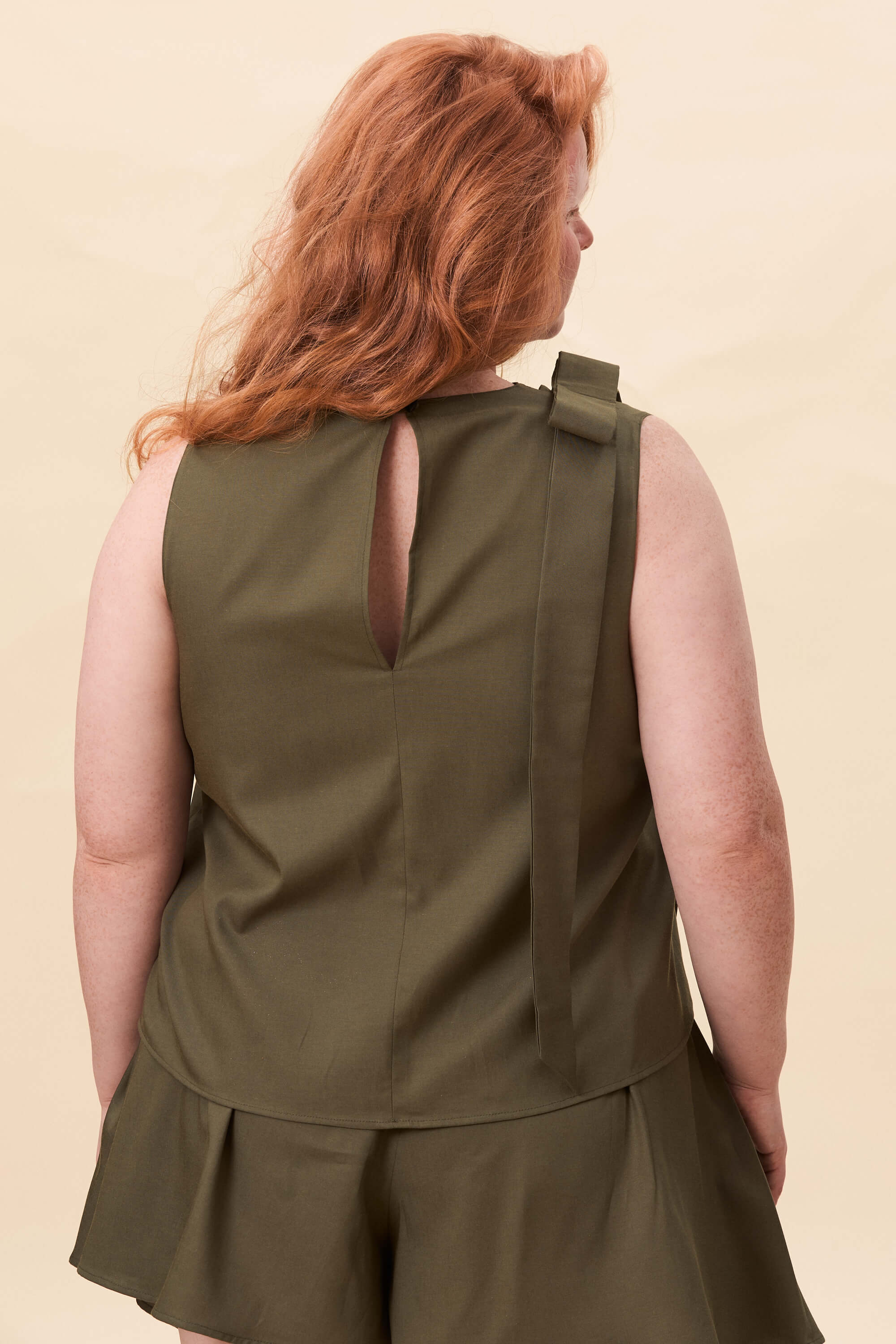 Spring 2026 Harriet Vane Top In Olive Green 5 Harriet Vane Top In Olive Green Harriet Vane top in olive green A sleeveless top with a clean, uninterrupted front. The silhouette is relaxed, allowing it to fall naturally or be tucked for a more defined shape. A narrow tie detail sits at the side, introducing structure without altering the clean lines.