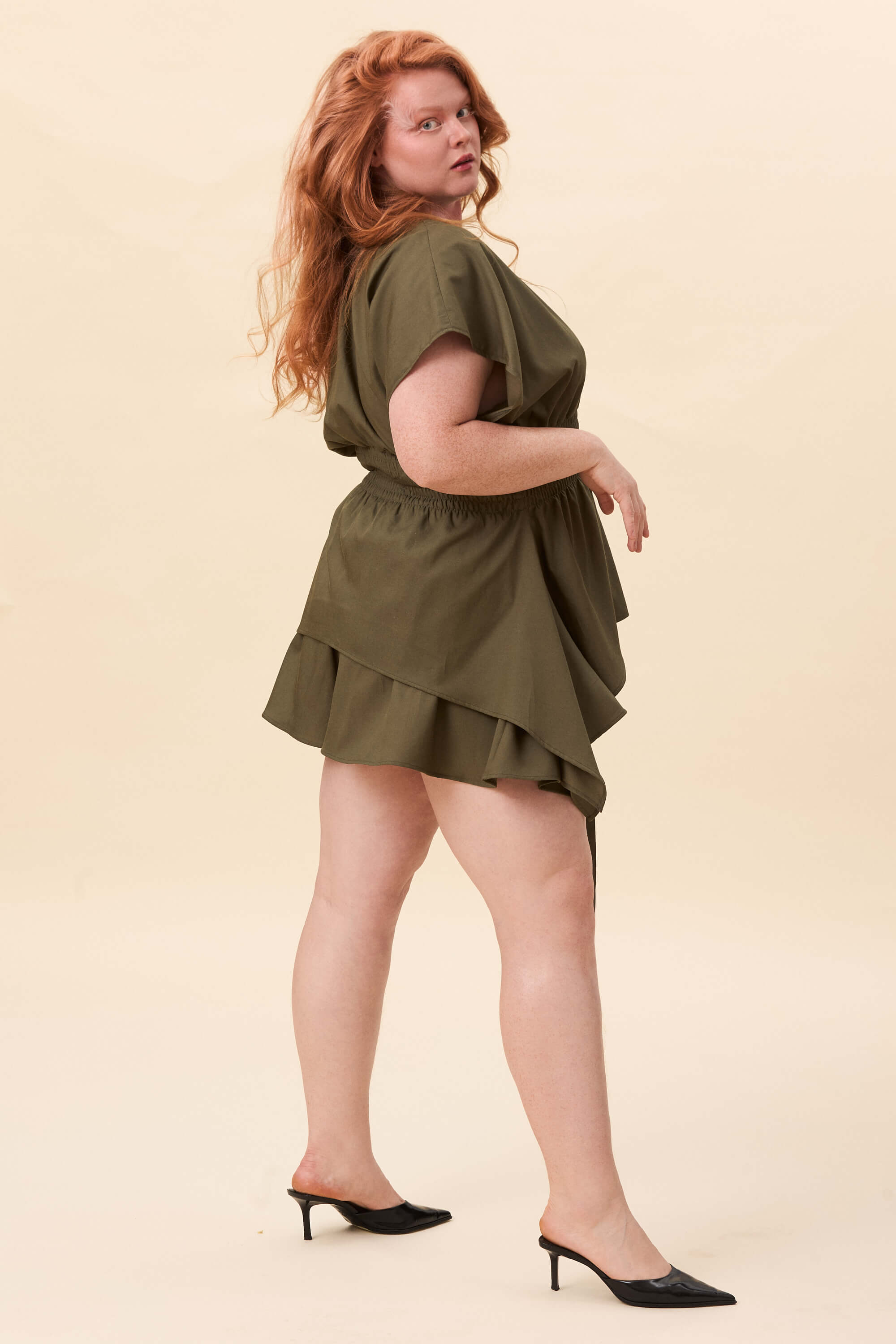 Spring 2026 Nemesis Ruched Top In Olive Green 4 Nemesis Ruched Top In Olive Green Nemesis ruched top in olive green A structured top defined by a deep V neckline and a shaped waist panel. The bodice is fitted through a smocked section, creating tension and adaptability. From the waist, the fabric releases into soft, pointed extensions that move away from the body.