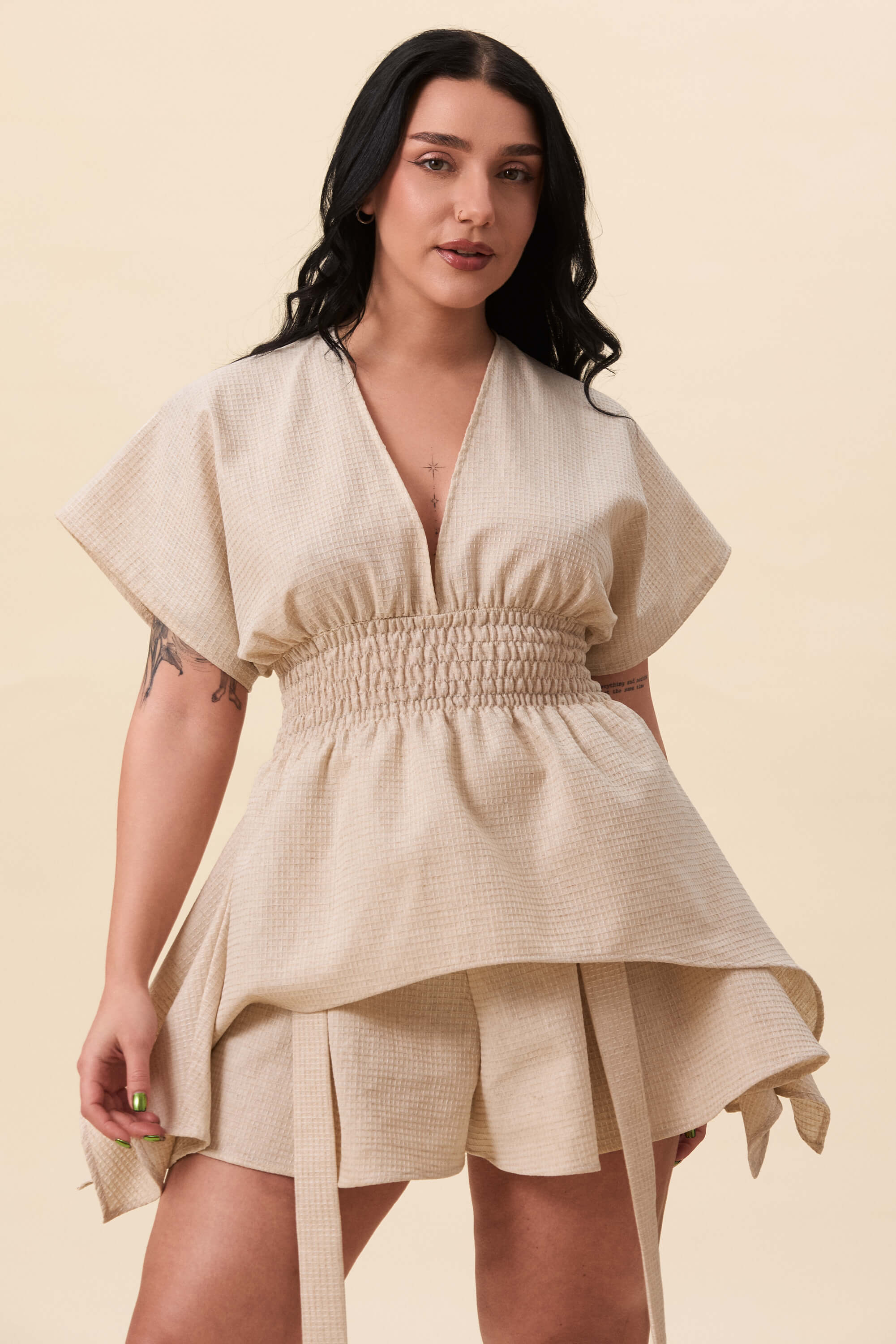 Spring 2026 Nemesis Ruched Top In Textured Beige 7 Nemesis Ruched Top In Textured Beige Nemesis ruched top in textured beige A structured top defined by a deep V neckline and a shaped waist panel. The bodice is fitted through a smocked section, creating tension and adaptability. From the waist, the fabric releases into soft, pointed extensions that move away from the body.