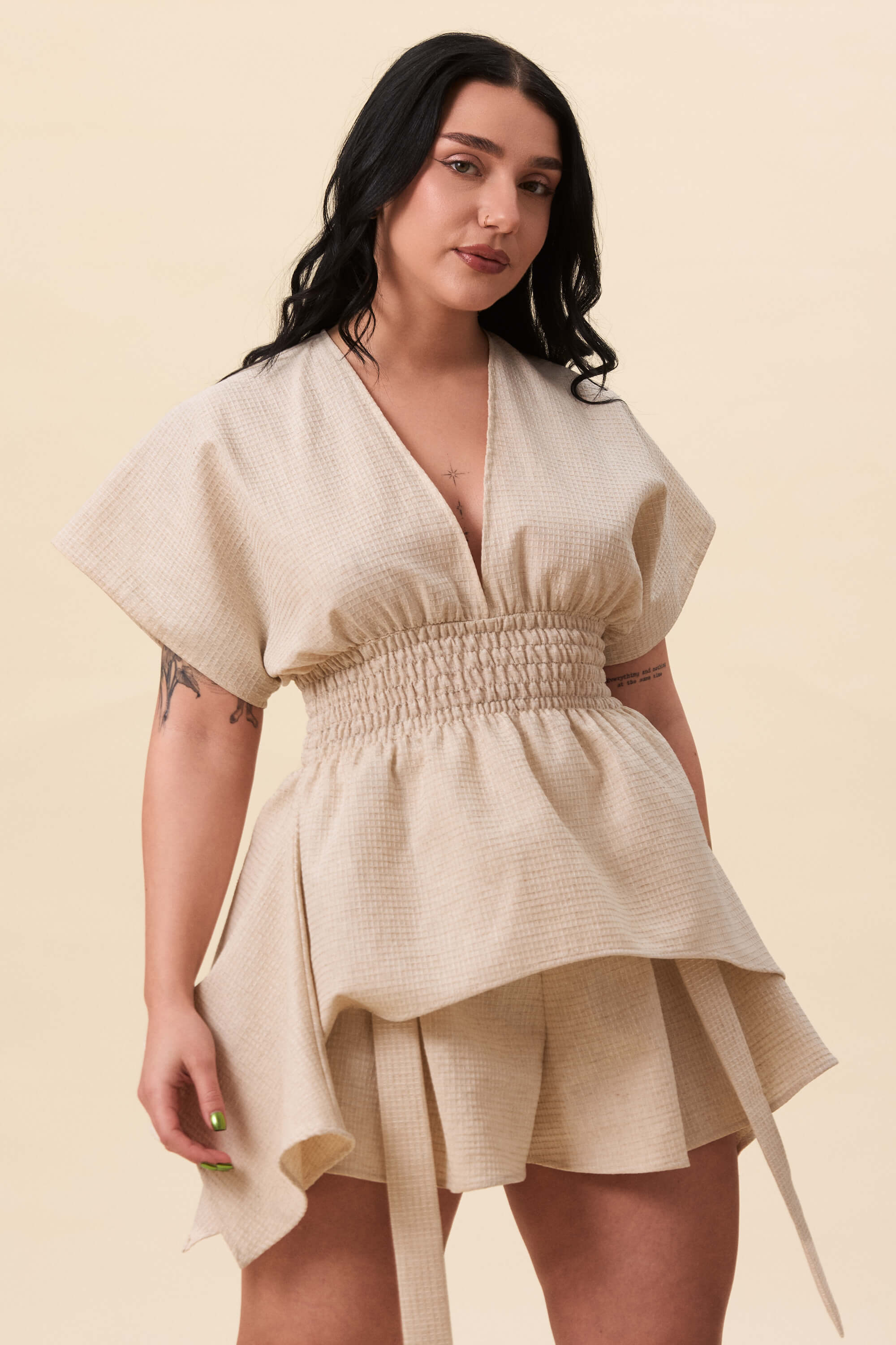 Spring 2026 Nemesis Ruched Top In Textured Beige 8 Nemesis Ruched Top In Textured Beige Nemesis ruched top in textured beige A structured top defined by a deep V neckline and a shaped waist panel. The bodice is fitted through a smocked section, creating tension and adaptability. From the waist, the fabric releases into soft, pointed extensions that move away from the body.