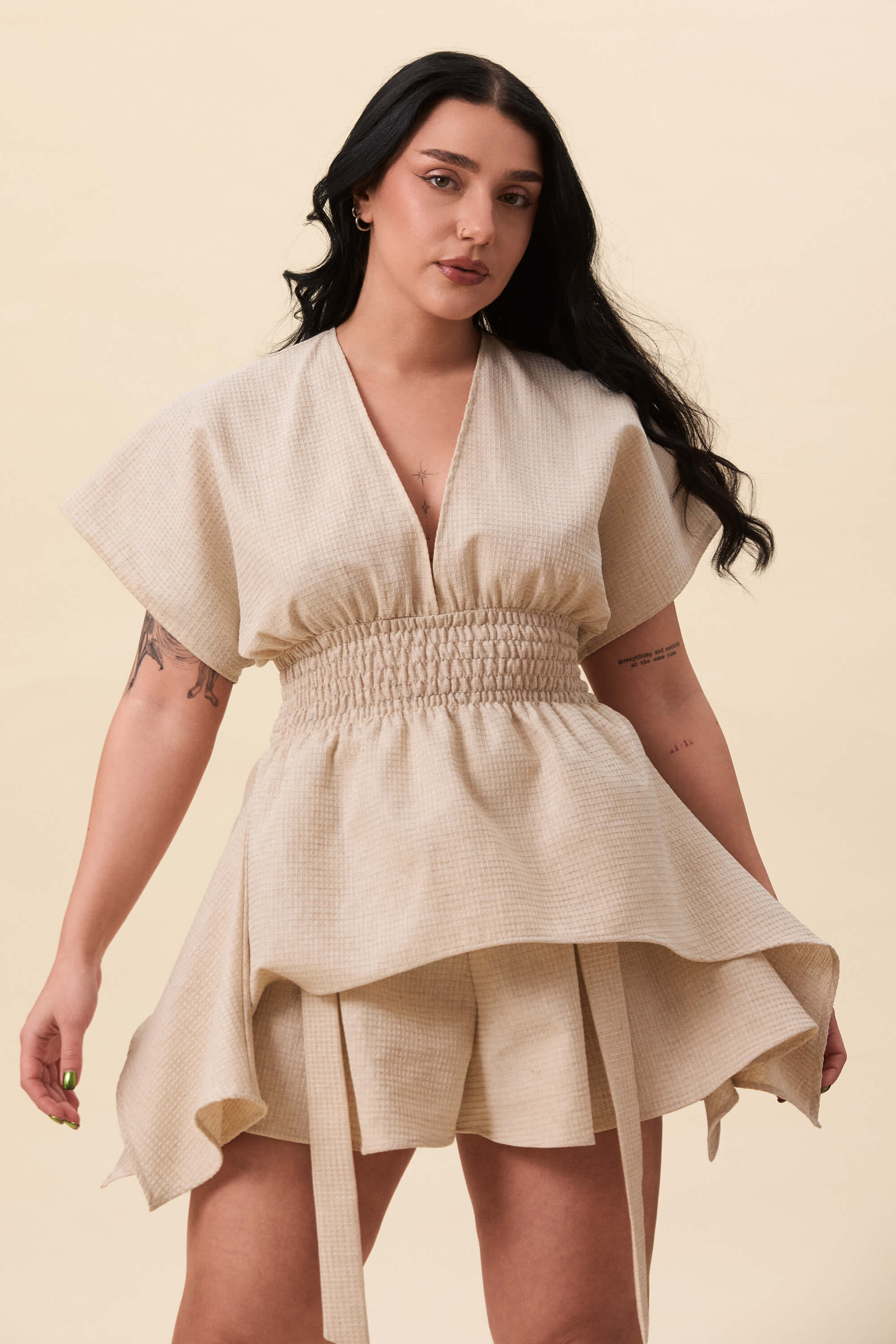 Spring 2026 Nemesis Ruched Top In Textured Beige 9 Nemesis Ruched Top In Textured Beige Nemesis ruched top in textured beige A structured top defined by a deep V neckline and a shaped waist panel. The bodice is fitted through a smocked section, creating tension and adaptability. From the waist, the fabric releases into soft, pointed extensions that move away from the body.
