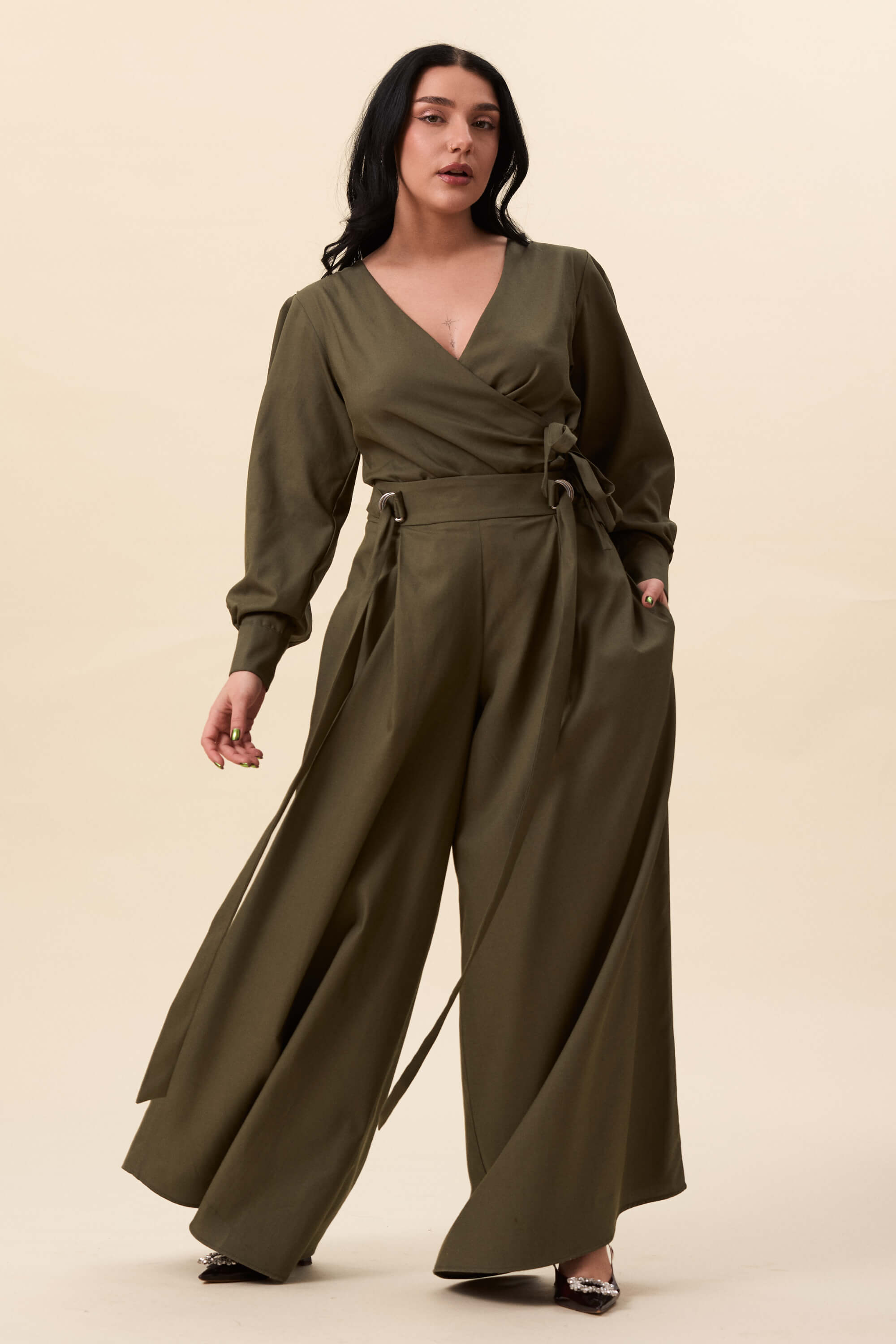 Spring 2026 Strong Poison Wrap Shirt In Olive Green 3 Strong Poison Wrap Shirt In Olive Green Strong Poison wrap shirt in olive green A wrap shirt shaped through angled lines rather than volume. The front crosses into a sharp, pointed hem, fastening with slender ties at the side. Sleeves are softly structured, finished with extended cuffs.