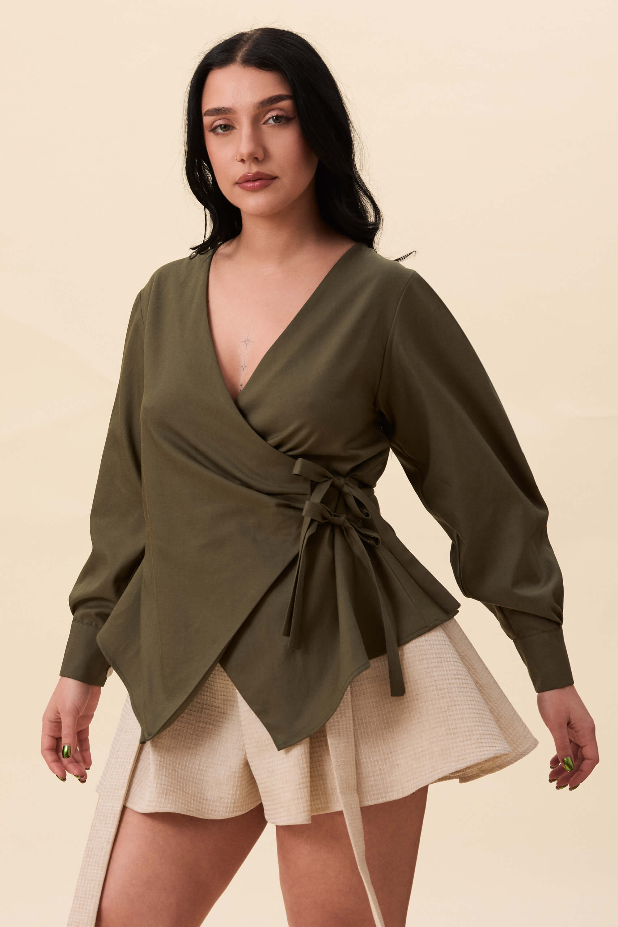 Spring 2026 Strong Poison Wrap Shirt In Olive Green 7 Strong Poison Wrap Shirt In Olive Green Strong Poison wrap shirt in olive green A wrap shirt shaped through angled lines rather than volume. The front crosses into a sharp, pointed hem, fastening with slender ties at the side. Sleeves are softly structured, finished with extended cuffs.