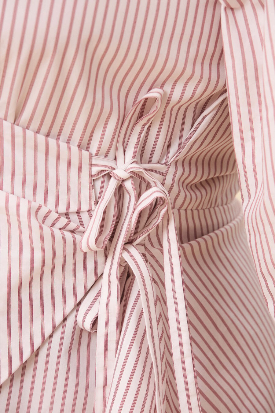 Strong Poison wrap shirt in red stripes - A wrap shirt shaped through angled lines rather than volume. The front crosses into a sharp, pointed hem, fastening with slender ties at the side. Sleeves are softly structured, finished with extended cuffs.