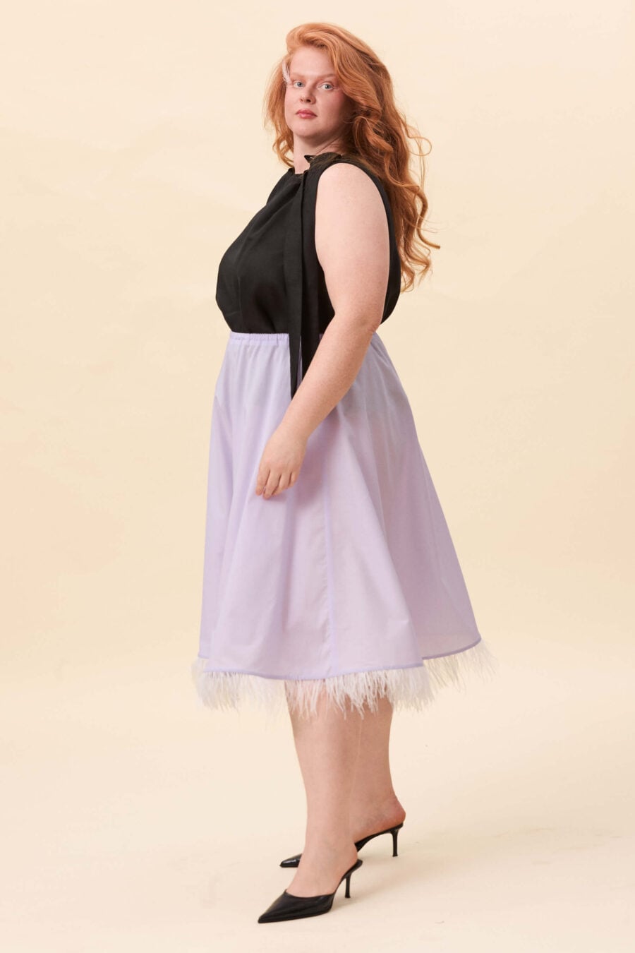 The Secret History skirt in lavender voille - A bias-cut skirt that follows the body with a fluid, uninterrupted line. The shape remains simple, allowing the drape to define the silhouette. Along the hem, a feather trim introduces movement and a soft shift in texture.