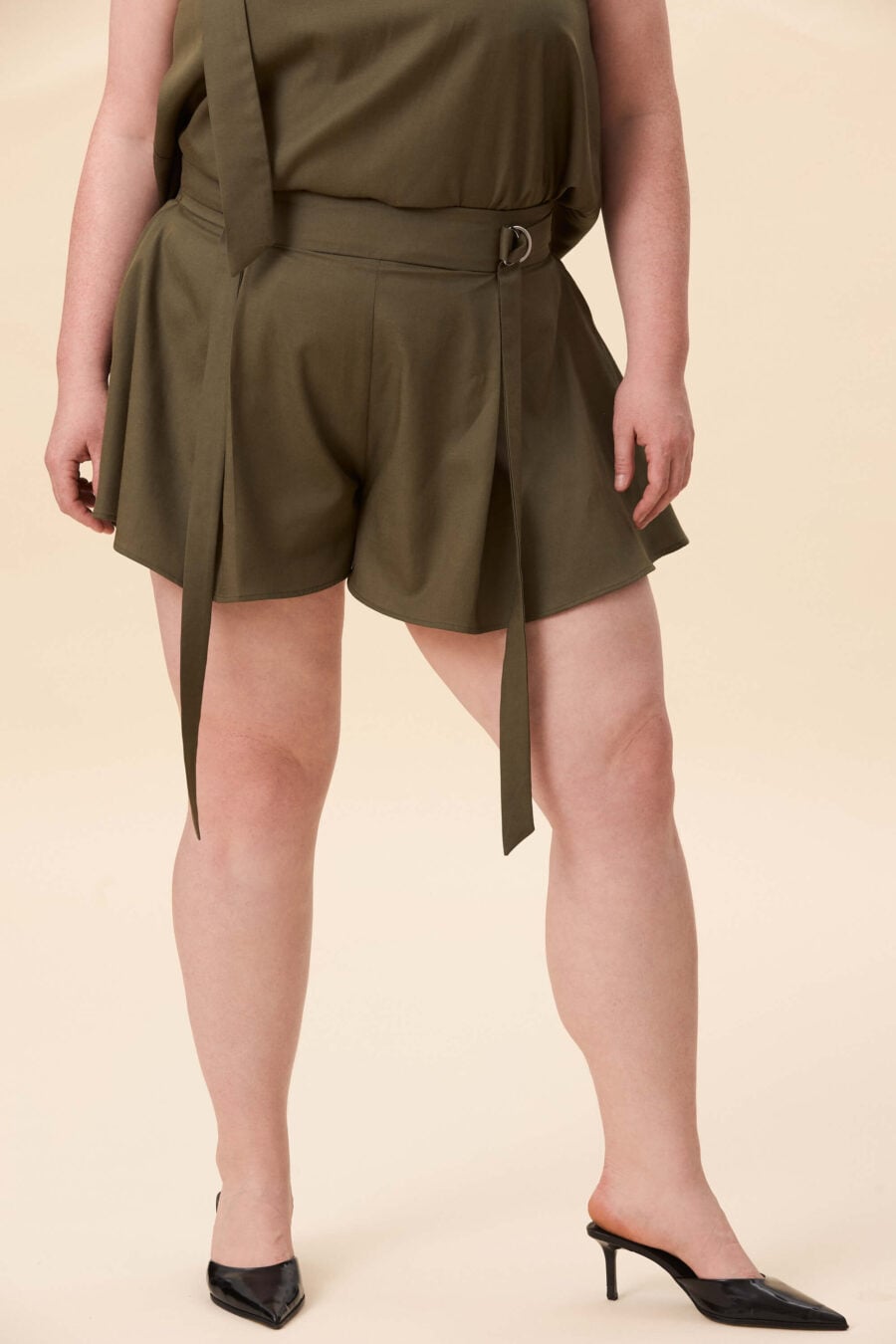 You Will Know Me shorts in olive green - Shorts cut with a structured waist and full, skirt-like volume through the leg. The waist is defined by an integrated belt, fastening through D-rings for adjustable fit. The shape opens freely, creating movement with every step.